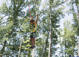 School boy preparing for zipline adventure.  Summer fun with climbing in mountains. Enjoying  time in climbing adventure park on warm and sunny summer day. Summer activities for young kids.
