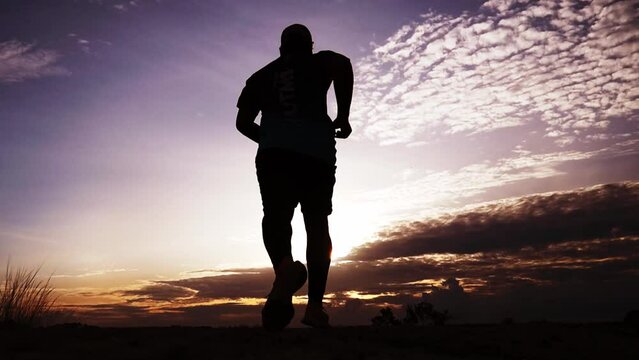 Silhouette of a man running in the mountains, fitness and health concept