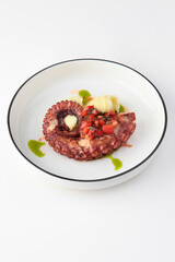 Grilled octopus with potatoes. Squid tentacles on white plate. Mashed potatoes with cream. White background.Copy space. Isolated object.Vertical photo.