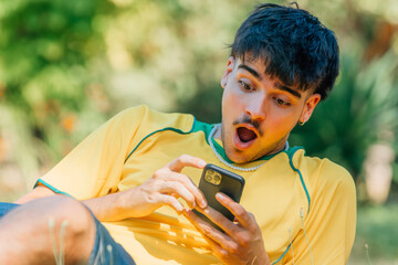 young man with mobile phone with surprised expression in the field