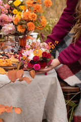 Autumn floral bouquet in a pumpkin vase for Halloween. Floral arrangement in woman's hands