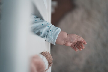 Hands of baby coming out of the cot when sleeping
