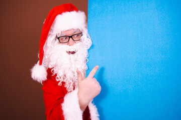 Funny Santa Claus posing with an advertising board on a brown background.