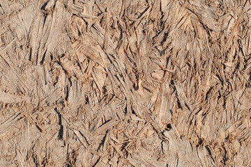 Chipboard plywood rough cracked surface close-up, background
