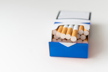 Cigarettes with orange filters in pack on table, closeup