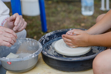 master class on modeling clay, creating a vase, bowl, pot on potter's wheels in the workshop. the master helps the child