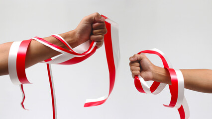 A man with a fist holding a red and white ribbon with empty copy space isolated on a white background, representing Indonesia Independence Day concept