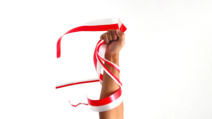A man with a fist holding a red and white ribbon with empty copy space isolated on a white background, representing Indonesia Independence Day concept