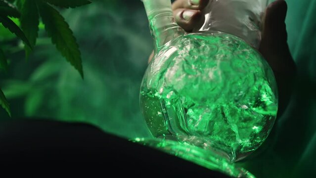 Smoking medical marijuana, glass water bong in neon light at home. Cannabis.