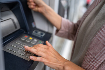 hands of woman using credit card and withdrawing cash at the ATM
