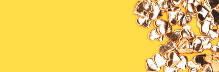 Banner with gold colored hearts confetti on a yellow background.