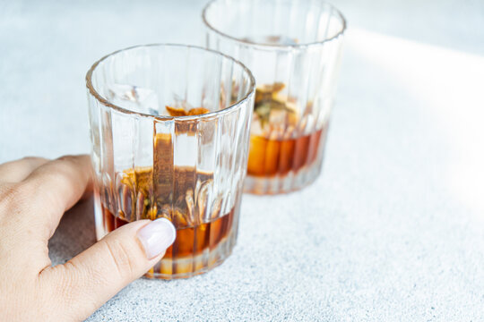 Anonymous person with glasses of whiskey with ice and orange peel