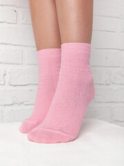 Girl in pink cotton socks on white wall background