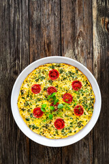 Omelette  - scrambled eggs with oregano, thyme, spinach and cherry tomatoes on wooden table
