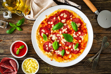 Upside down pizza with salami, mozzarella cheese and tomato sauce on wooden table
