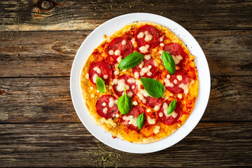 Upside down pizza with salami, mozzarella cheese and tomato sauce on wooden table