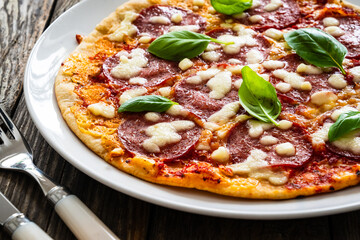 Upside down pizza with salami, mozzarella cheese and tomato sauce on wooden table
