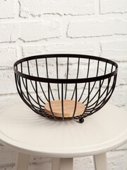 Metal fruit basket on white wall background. Home and kitchen decor