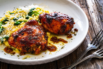 Greek style roasted chicken thighs with kritharaki rice and spinach on wooden table
