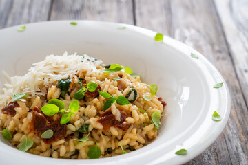 Risotto with sun dried tomatoes and Parmigiano Regiano  on wooden table
