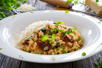 Risotto with sun dried tomatoes and Parmigiano Regiano  on wooden table
