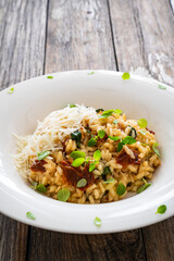 Risotto with sun dried tomatoes and Parmigiano Regiano  on wooden table
