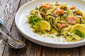 Tagliatelle with salmon and dill on wooden table

