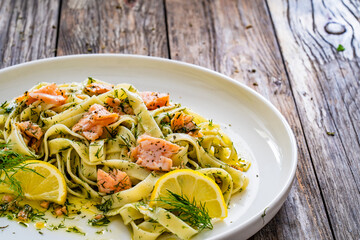 Tagliatelle with salmon and dill on wooden table
