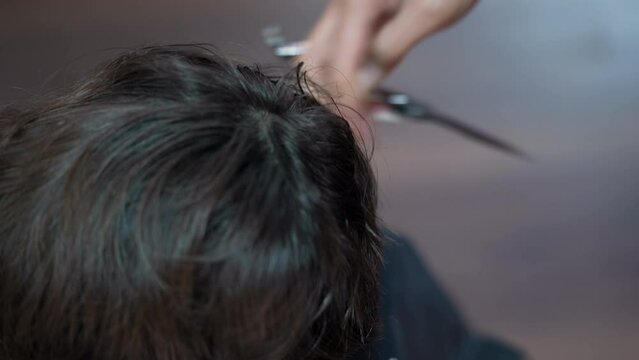 Hand Cutting Hair with Scissors and Comb in Close-up View.