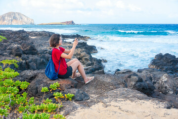 Young woman on lava rocks by ocean in Hawaii