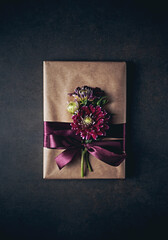Book wrapped as a gift with Dahlia flowers and satin ribbon. Top view
