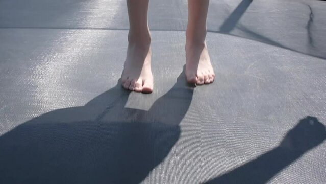 Close up view on children's feet bouncing on a trampoline. Slow motion full HD video of Children's legs are bouncing on the trampoline.