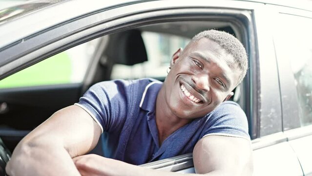 African american man smiling confident sitting on car doing victory gesture at street