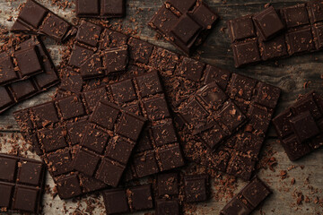 Pieces and shavings of tasty chocolate bars on wooden table, flat lay