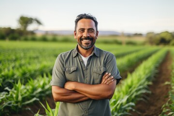 Naklejka na ściany i meble middle aged male mexican farmer smiling and working on a farm field portrait