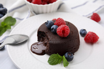 Delicious chocolate fondant, berries and mint on plate, closeup