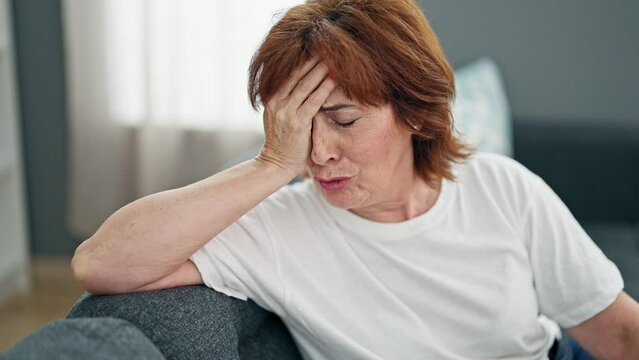 Middle age woman stressed sitting on sofa home