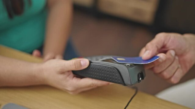 Two coworkers using credit card on dataphone at ecommerce office