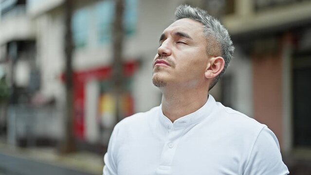 Young hispanic man breathing with closed eyes at street