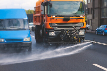 Municipal watering truck machines washes asphalt, process of street disinfection and cleaning from...