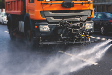 Municipal watering truck machines washes asphalt, process of street disinfection and cleaning from...