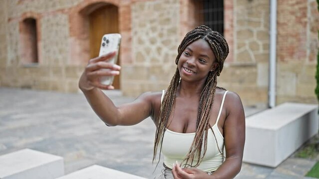 African american woman make selfie by smartphone sitting on bench at street