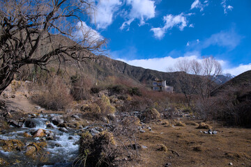 PAISAJE DE MONTAÑA CON UN ARROYO DE PIEDRA Y UNA CASA 