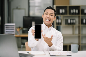 Successful business man, excited young man Keeping up arms and showing positive emotions, happy working in modern office on smartphone.