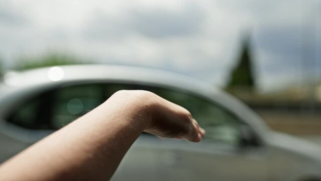 Young beautiful hispanic woman with arm out of the car window on the road