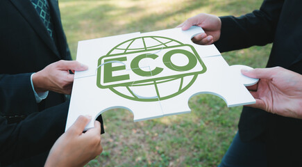 Business people or corporate partnership joining ECO friendly idea puzzle of jigsaw together as...