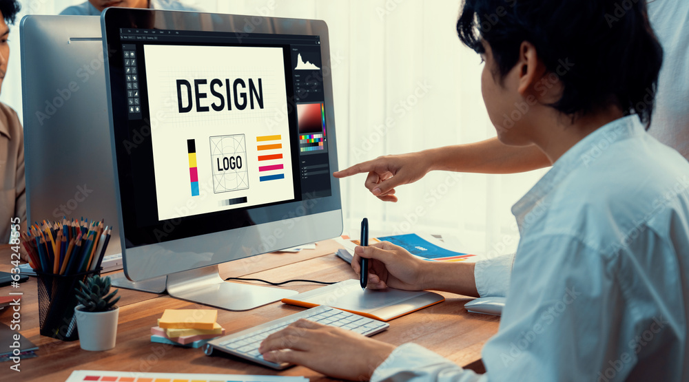 Poster Graphic designer work on computer laptop and with graphic drawing pen while brainstorming unique design with professional graphic team in modern digital studio workplace. Panorama shot. Scrutinize