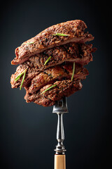 Grilled beef steak on a fork sprinkled with rosemary.