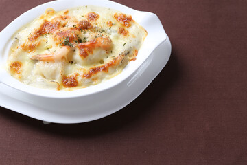 oven baked creamy cheese carbonara cream sauce pasta noodle with fresh big prawn seafood chicken chop in bowl on brown cloth white background design western chef cuisine halal food menu for cafe