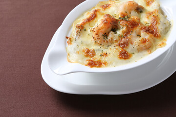 oven baked creamy cheese carbonara cream sauce pasta noodle with fresh big prawn seafood chicken chop in bowl on brown cloth white background design western chef cuisine halal food menu for cafe